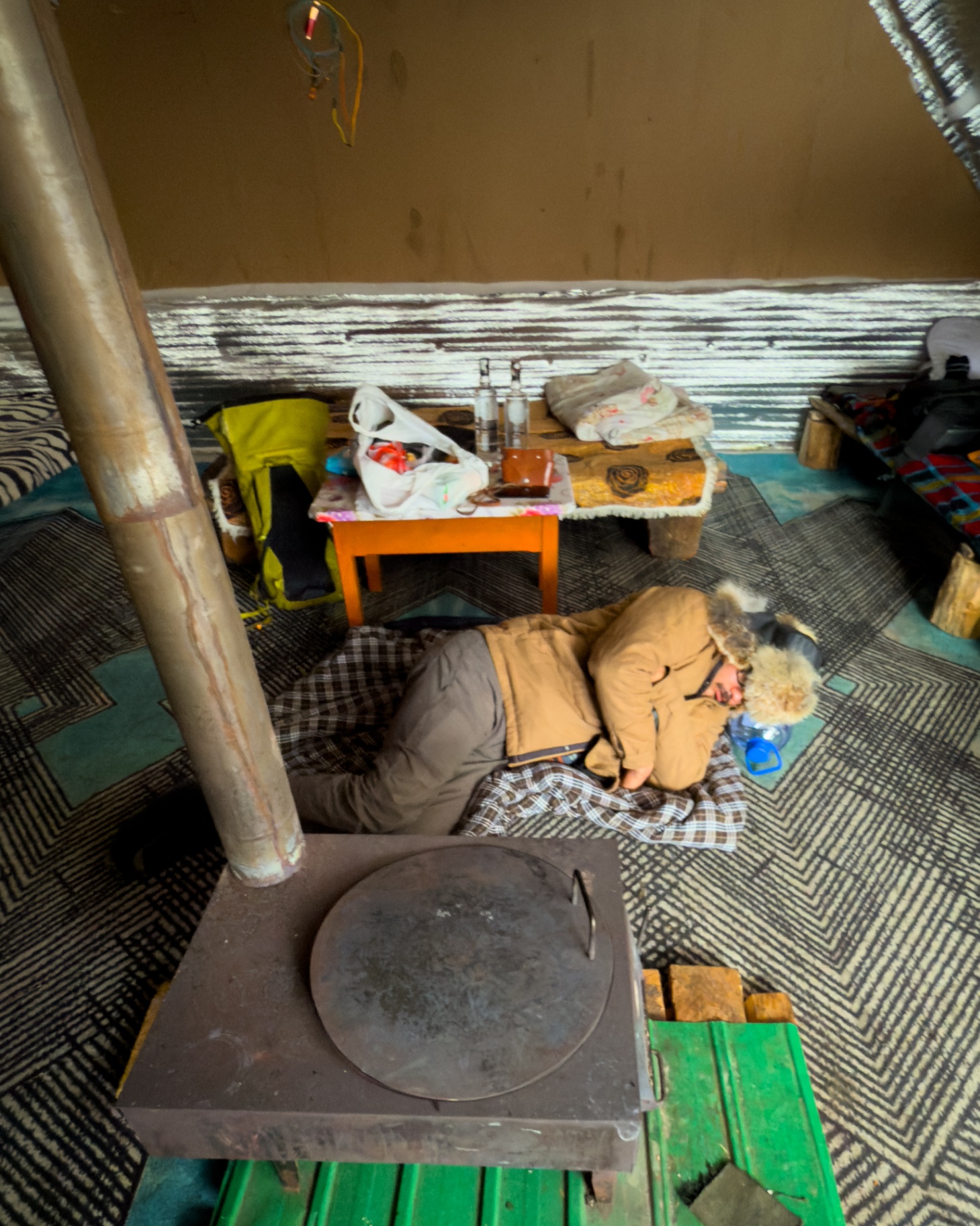 Simple sleeping quarters and wood stove inside a winter camp
